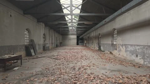 A spacious abandoned factory featuring skylights, arched windows, and scattered Stock Footage 329715371