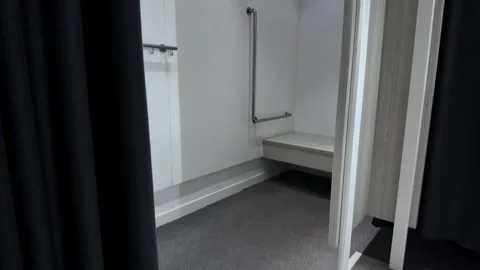 Spacious accessible fitting room with grab bars and a sturdy bench provides.. Stock Footage 318008709