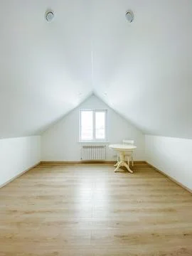 In the spacious and empty attic, there exists a simple yet functional table.. Stockfoto's