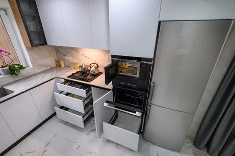 A spacious and updated kitchen with a white color scheme, a marble floor, an Foto stock