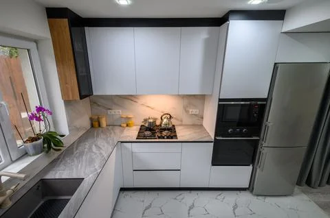 A spacious and updated kitchen with a white color scheme and marble floor Stock Photos
