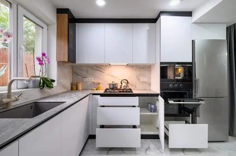 A spacious and updated kitchen with a white color scheme, a marble floor, an Stock Photos