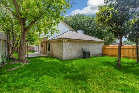 The spacious backyard has lush grass and trees, providing beauty Stock Photos