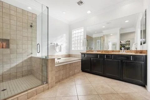 A spacious bathroom featuring two sinks, a tub, and a walkin shower Stock Photos