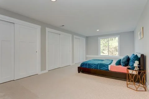 Spacious bedroom with built in closets in front of a blue bed. Stock Photos
