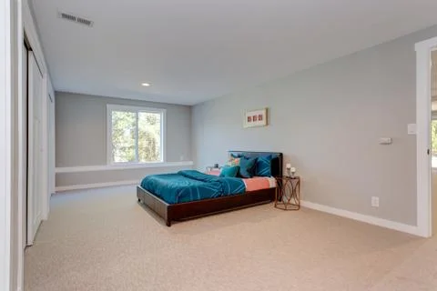 Spacious bedroom with built in closets in front of a blue bed. Stock Photos
