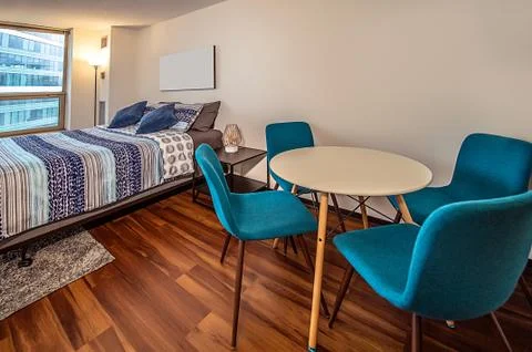 Spacious bedroom with large windows, double bed, sofa, table and chairs in br Stock Photos