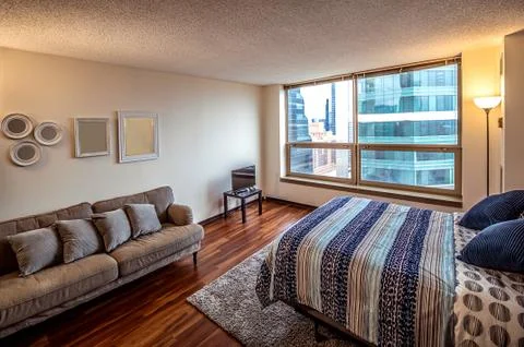 Spacious bedroom with large windows, double bed, sofa, table and chairs in br Stock Photos