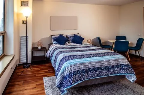 Spacious bedroom with large windows, double bed, sofa, table and chairs in br Foto stock