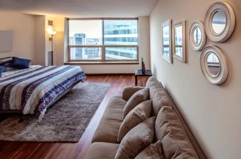 Spacious bedroom with large windows, double bed, sofa, table and chairs in br Foto stock