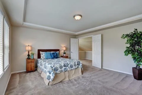 Spacious bedroom with queen size bed, floral patterned bedding with blue pillows Stock Photos