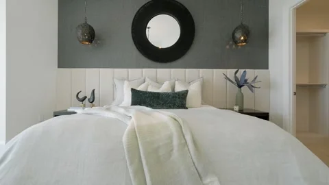 Spacious bedroom in soft colors featuring large bed with tufted headboard and Stock Footage 273832087