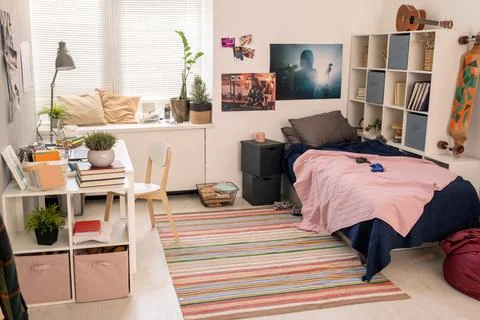 Spacious bedroom of teenage student with bed, desk with lamp and laptop and Stock Photos
