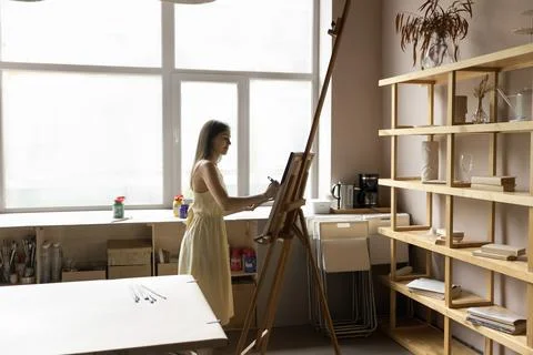 In spacious creative workshop young female drawing on easel Stock Photos