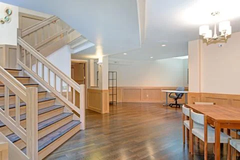 Spacious dining room features white ceiling over a wood dining table surround Stock Photos