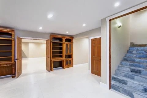 Spacious empty basement area with custom built bookcases and a view of stone  Stock Photos
