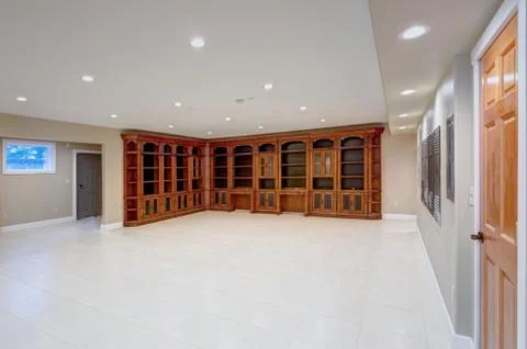 Spacious empty basement area with large custom built bookcase. Luxury lifesty Stock Photos