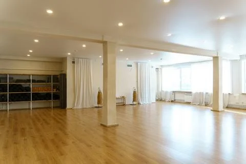 A spacious empty hall with columns and large windows. A gym with wooden floor Stock Photos