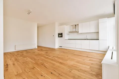 A spacious empty room with a corner kitchen on parquet floors Stock Photos