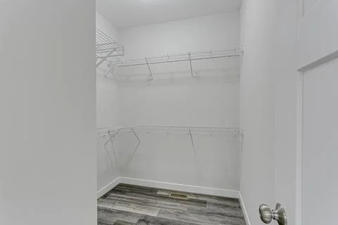 Spacious Empty Walk-In Closet With Wire Shelves And Wooden Flooring. Stock Photos