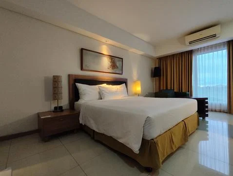 A spacious hotel room featuring a large bed with crisp white linens Stock Photos