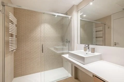 Spacious interior of modern tiled bathroom with white sink, large mirror and Stock Photos