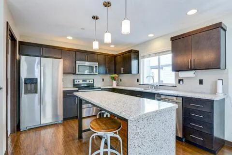 Spacious kitchen with open floor plan features chocolate brown cabinets and a Stock Photos