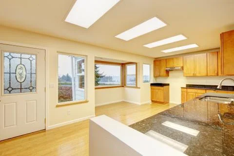 Spacious kitchen room with light brown cabinets and black granite counter top Stock Photos