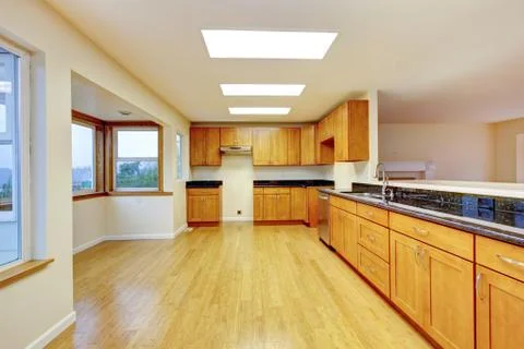 Spacious kitchen room with light brown cabinets and black granite counter top Stock Photos