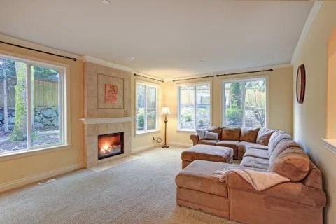 Spacious light living room features classic fireplace with beige tile surroun Stock Photos