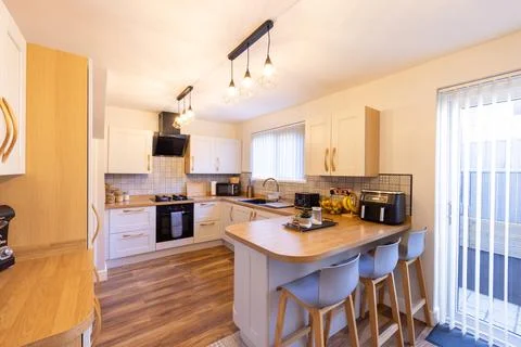 Spacious modern fitted kitchen with white cabinets wooden worktops curved b.. 库存照片