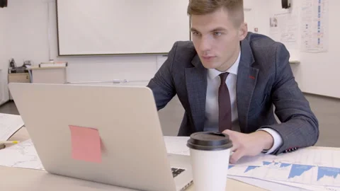 In spacious office at desk young man is working behind a laptop. Stock Footage 85644058
