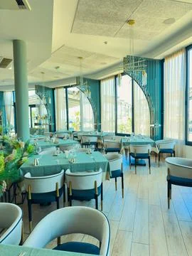 A spacious restaurant with neatly arranged tables and chairs waits for guests Stock Photos