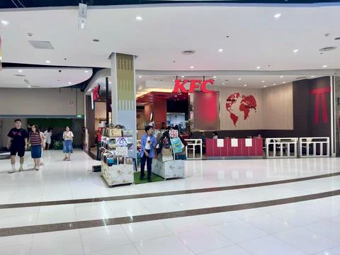 Spacious shopping corridor featuring KFC restaurant and handbag stall inside Stock Photos