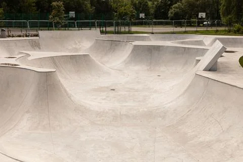 A spacious skate park features smooth concrete curves and ramps, inviting s.. Stock Photos
