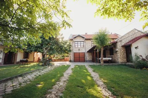 Spacious Stone Courtyard Framed By Trees And Trimmed Lawn, Dual Grass Tracks Фото