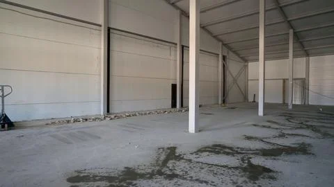 Spacious unfinished warehouse interior with structural columns, wet concret.. Stock Photos