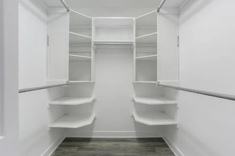 Spacious White Walk-In Closet With Multiple Shelves And Hanging Rods. Stock Photos