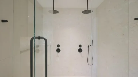 Spacious wlak-in bathing area with double shower mixers and dark plumbing with Stock Footage 280419284