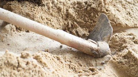 A spade placed on a sandy construction. Stock Photos