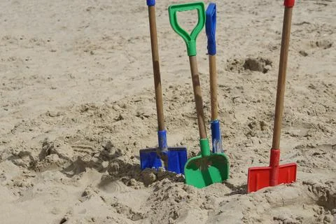Spades digging in the sand at a beach Stock Photos