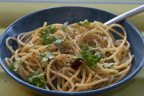 Spaghetti aglio olio e peperoncino with fresh parsley in blue bowl Stock Photos