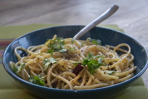 Spaghetti aglio olio e peperoncino with fresh parsley in blue bowl Stock Photos
