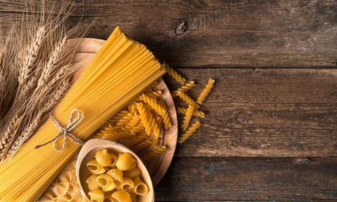Spaghetti and different types of pasta on a wooden background. Stock Photos