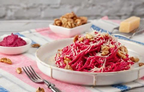 Spaghetti with beetroot pesto sauce, walnuts and parmesan on a light backgrou Foto stock