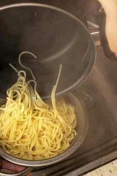 Spaghetti being poured into a colander. vertical photo Stock Photos
