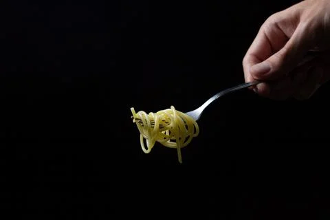 Spaghetti on a black background. Boiled spaghetti on a fork. Isolated spaghetti. Stock Photos