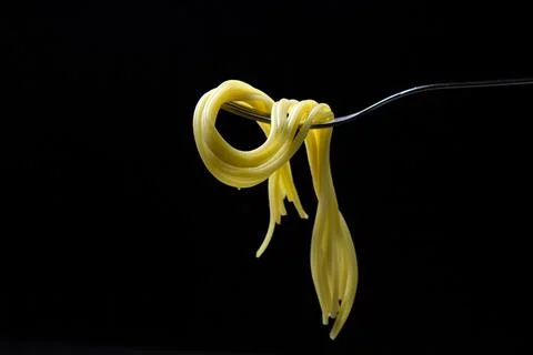 Spaghetti on a black background. Boiled spaghetti on a fork. Isolated spaghetti. Stock Photos