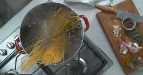 Spaghetti boiling in a large pot of water, over a gas powered stove with a chopp Stock Footage 199457969