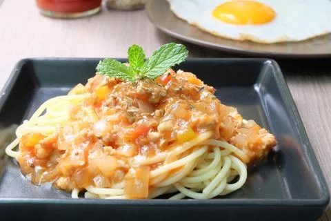 Spaghetti bolognese in black plate with Fried Egg Stock Photos
